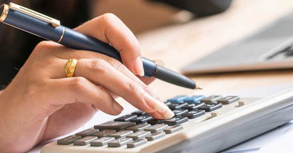 Guides hand holding a pen and using a calculator