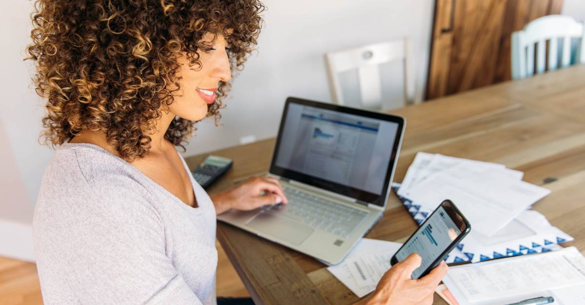 lady in front of laptop holding phone