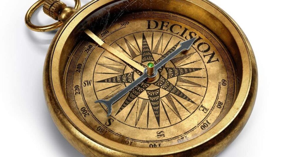 old gold coloured compass pointing to the word decision